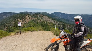 A motorcycle rider stops to take in the view along a trail at the top of a mountain ridge. (Photo by Eric Coulter, BLM)