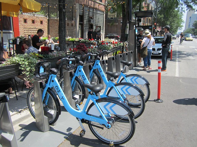 three people wait in line at a Divvy station