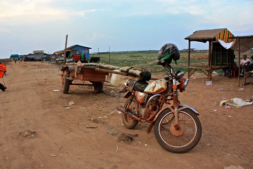 there is a cart attached to this motorbike by a huge bamboo log