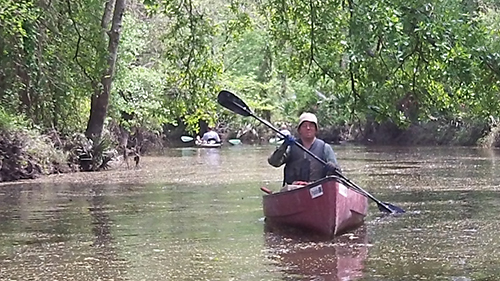 Kayakers heading away downstream behind the canoe