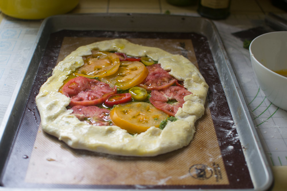 Layer tomato slices over the pesto, overlapping if needed. Fold edges over forming a tart.