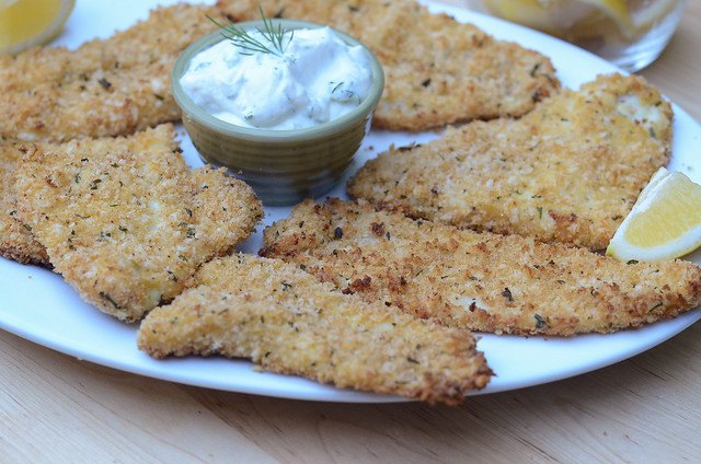 A plate with crispy breaded fish and creamy dill sauce.