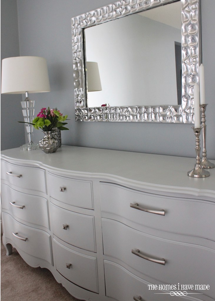 A dresser styled with modern decor in a master bedroom