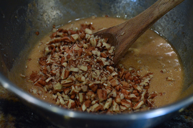 Chopped nuts are added to other ingredients in a mixing bowl.