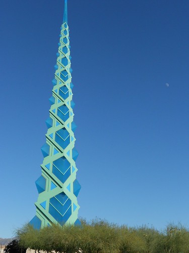 a pointy tower shoots out of the ground, as a distant moon watches over the scene, bottomed out with grass