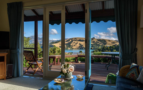 newzealand southisland bankpeninsula canterbury akaora scene water sea hills sky trees houses buildings architecture akaorahabour roses table chair deck view windows doors reflections interior