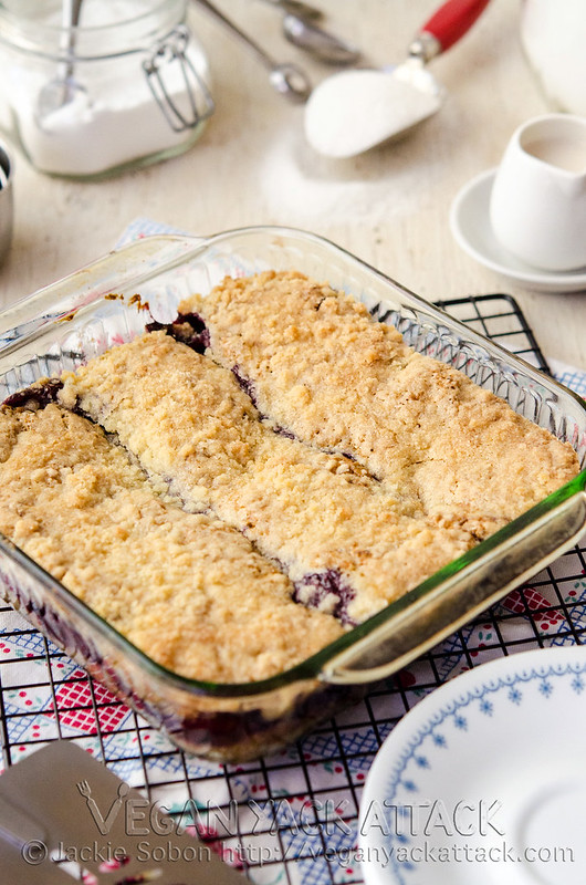 Baked mixed berry coffee cake on a cooling rack surrounded by plates and ingredients