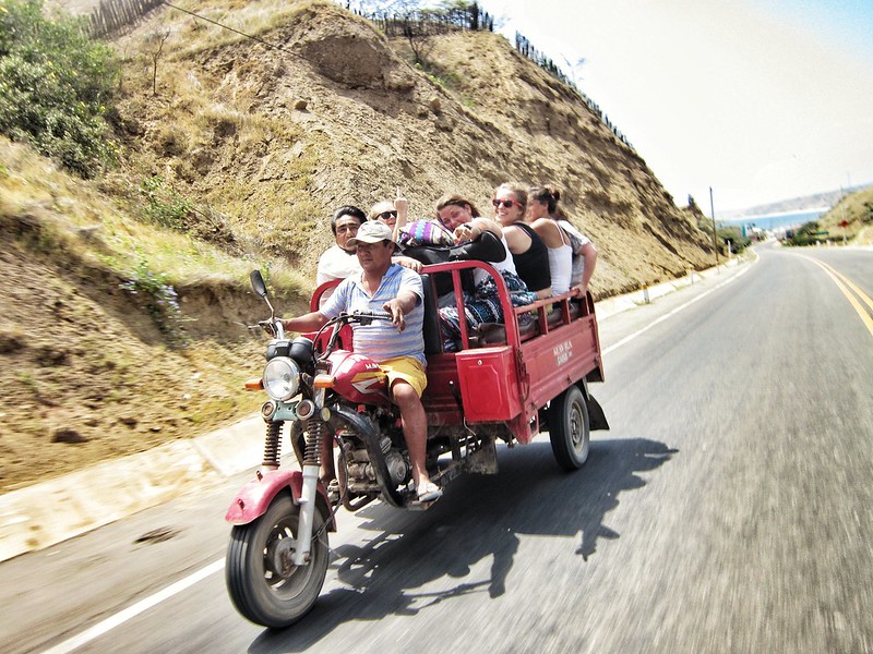 A group of Westerners ride in the back of a motorbike truck 