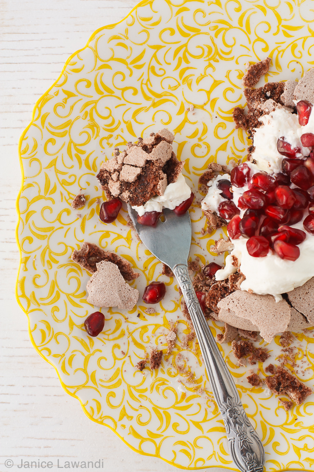 chocolate pavlova with whipped cream and pomegranate seeds.