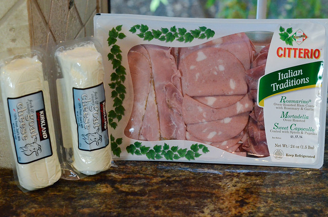 Meats in a package next to a logs of goat cheese.