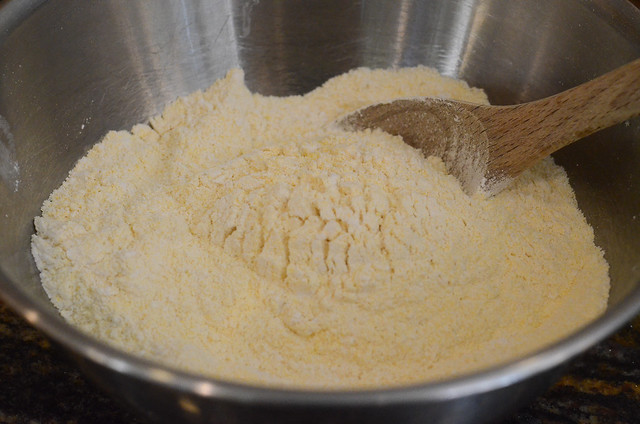 Cornmeal in a bowl with a spoon.