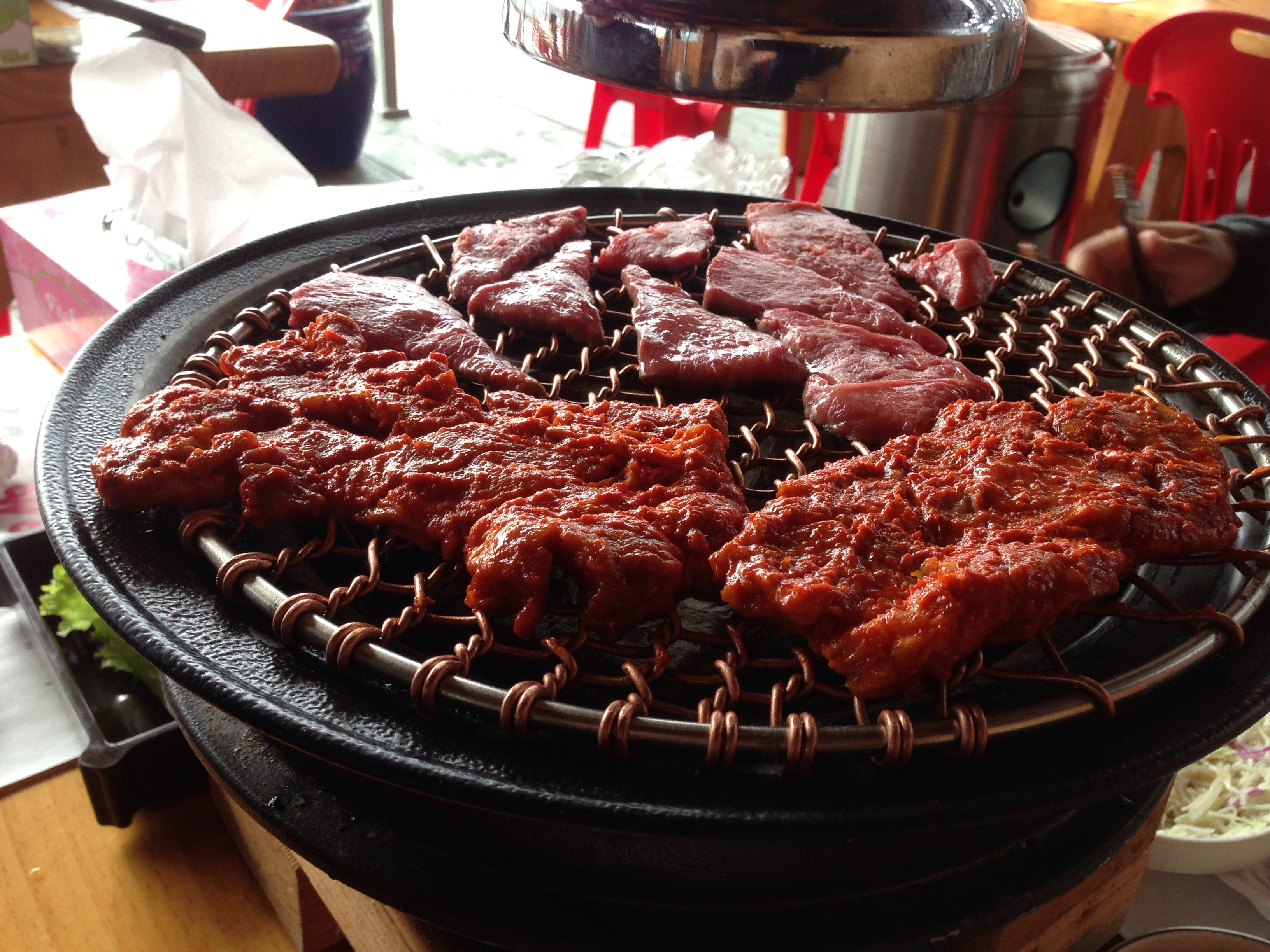 Korean table top barbecue, topped with marinated meats.