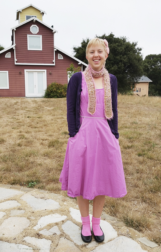 wearing a pinky-purple dress in front of a barn
