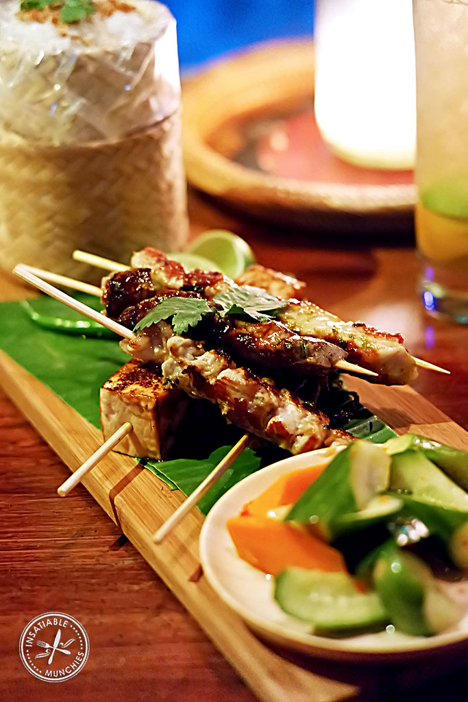 A selection of skewers from the menu is served on a platter with house pickles and steamed coconut rice in a bamboo basket. 