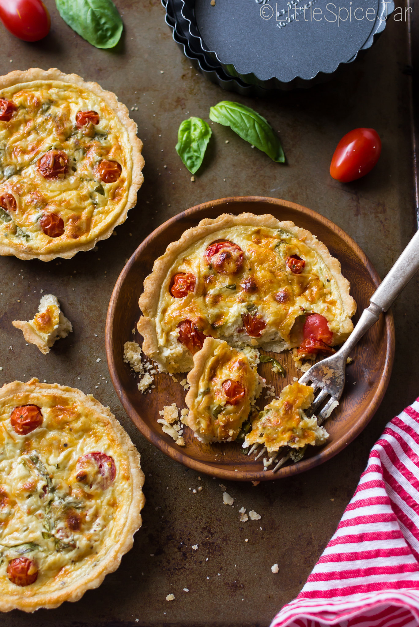prepared quiche on wood plates with fork on sheet pan surface