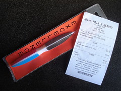 A nail file of triangular cross-section, with different grades of sandpaper on each side, inside a clear-fronted packet with a red back.  Lying on top is a receipt showing 99p paid for some “pony tail holders”.