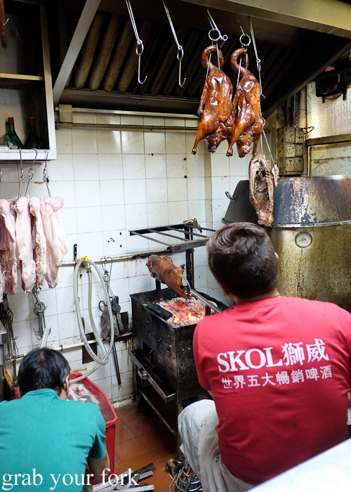 Crisping the suckling pig by hand over charcoal at Tai Chung Wah, Cheung Sha Wan, Hong Kong