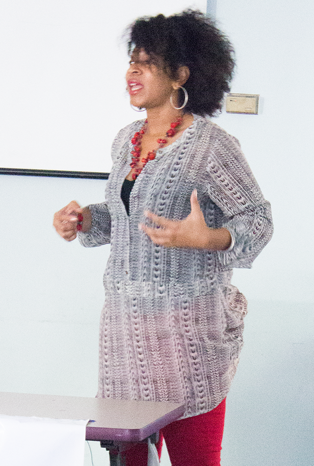 public speaking, natural dark curly hair, patterned red-and-black outfit