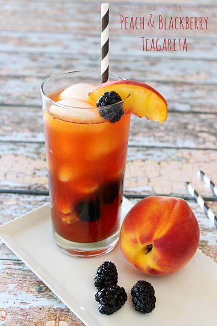Peach & Blackberry Teagarita in a glass with a straw and fresh peaches and blackberries.