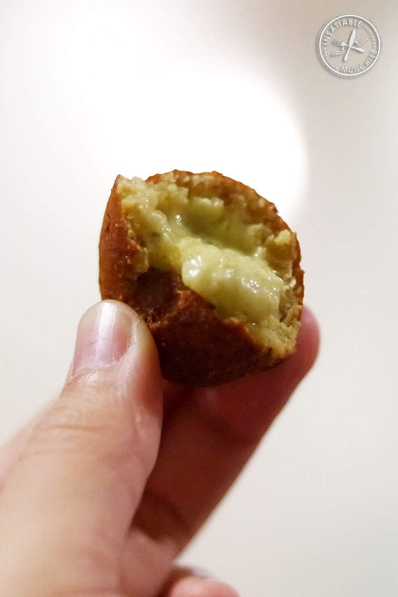 A jalapeño and cheese popper is bitten open, to reveal the filling inside.