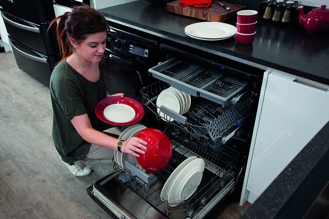 Woman loading black freestanding dishwasher