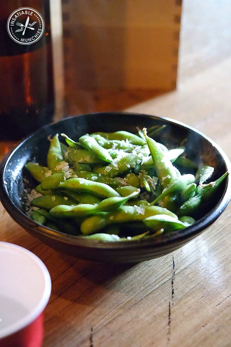 Steamed edamame beans - Japanese green soy beans - are served warm, and topped with sea salt flakes.