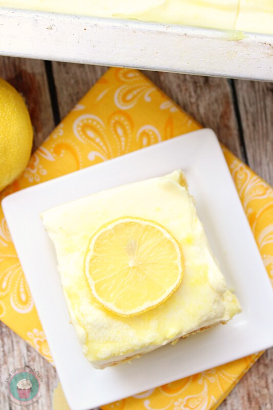 Lemon Supreme Cake on a plate with a lemon slice on top.