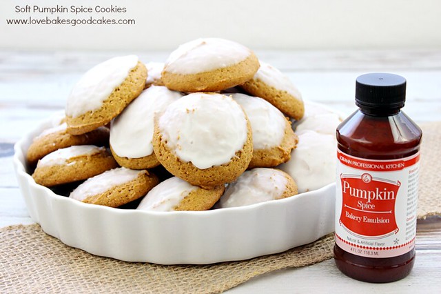 Soft Pumpkin Spice Cookies in a white dish with pumpkin spice bottle next to them.