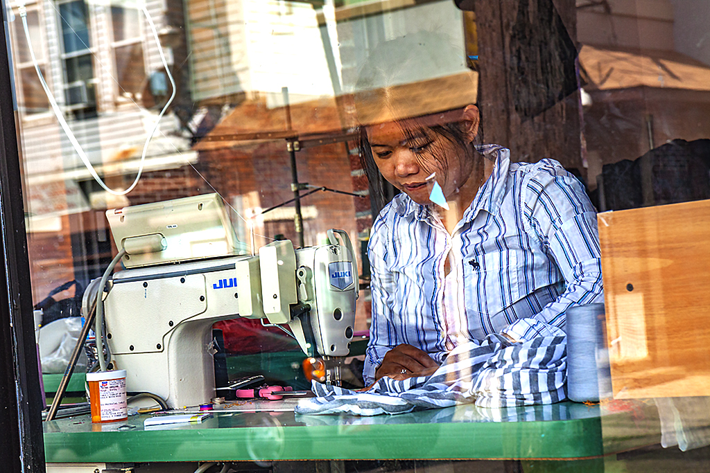 Woman-sewing-in-Little-Cambodia-window-on-6-8-14--South-Philly