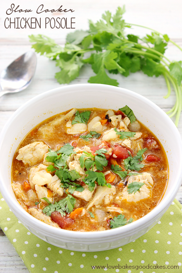 Slow Cooker Chicken Posole in a white bowl with cilantro and a spoon.