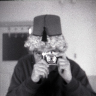 reflected self-portrait with Taxona camera, curly hair and fez