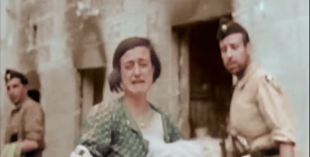 Una mujer llora con su hijo en brazos junto al Alcázar durante el asedio. Captura de un vídeo real a color de la Guerra Civil en Toledo en el verano de 1936