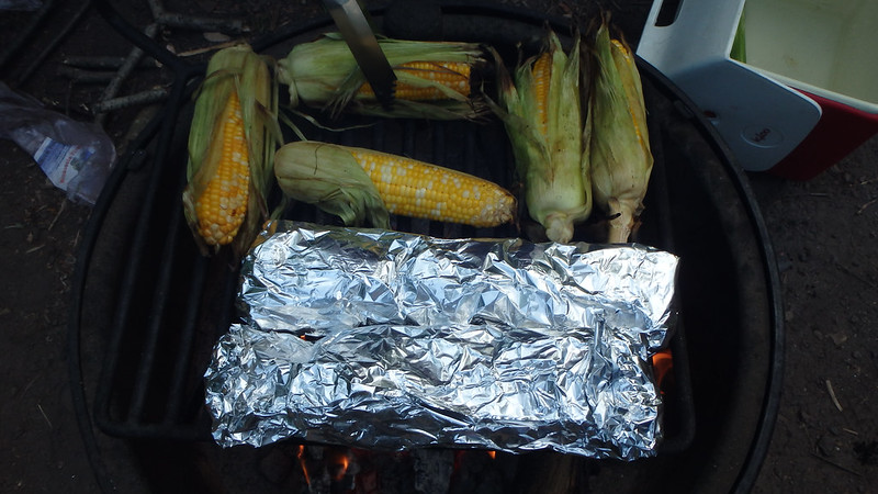 sweet corn and packets of potatoes and onions on the campfire