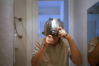 reflected self-portrait with Olympus XA camera and holey metal hat