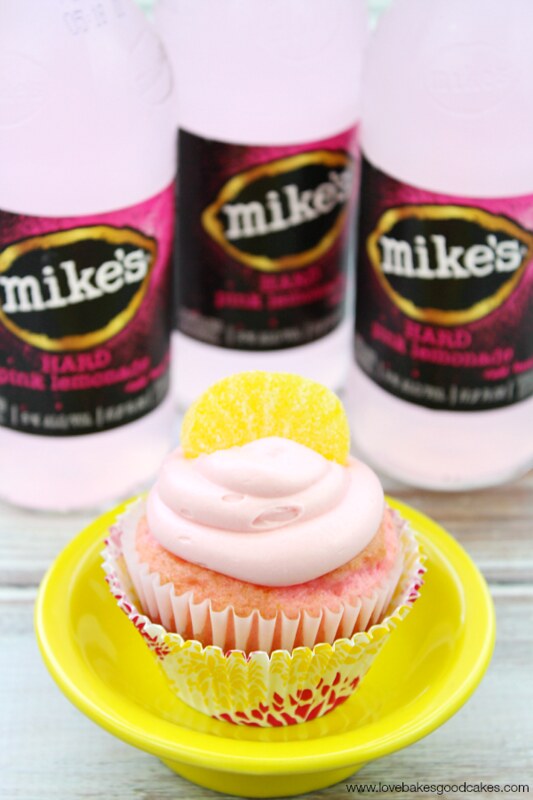mike's hard pink lemonade® cupcake with three bottles of Mike's Hard Lemonade behind it.