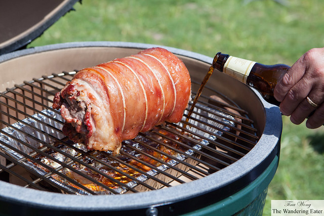Adding beer to the bacon wrapped porchetta in the Big Green Egg