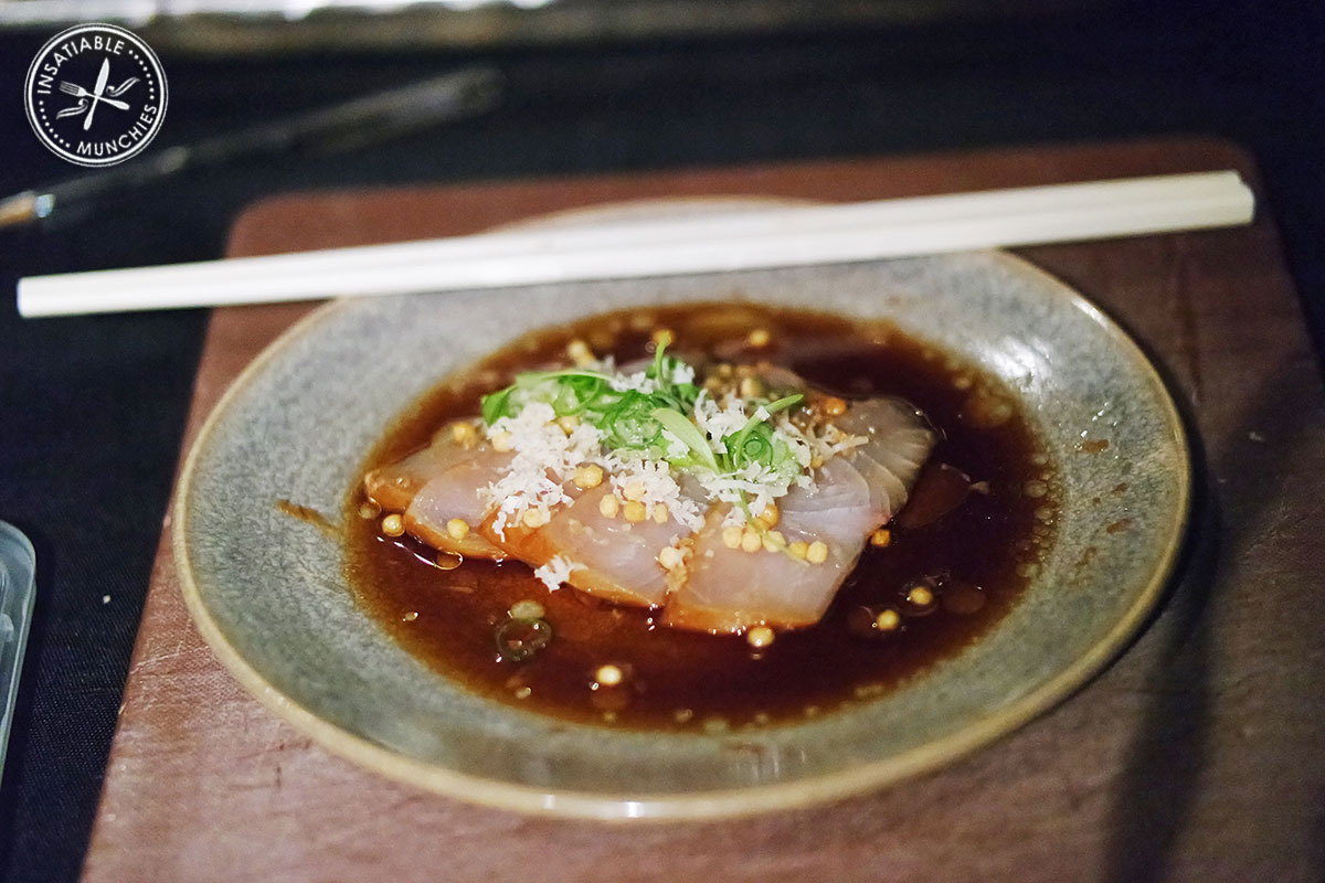 Slices of soy cured hiramasa kingfish, topped with a ginger and shallot dressing, soy based sauce, black garlic oil, micro herbs and fresh grated horseradish.