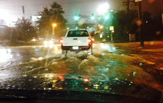Picture of a truck driving on a flooded street.
