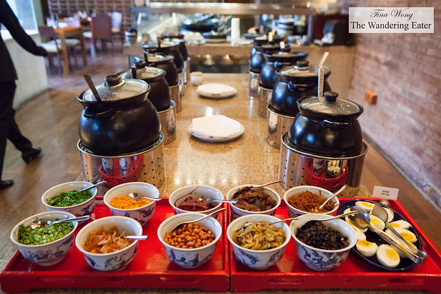 Small pots of various congees, soups and soybean milk and a topping bar at Made in China's breakfast buffet