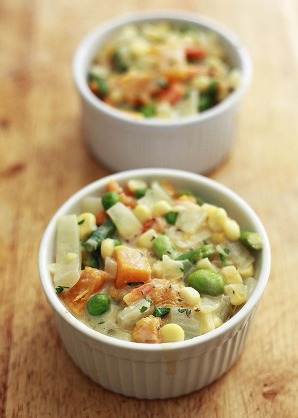 Ramekins are filled with vegetable pot pie filling before getting topped with pie crust. 