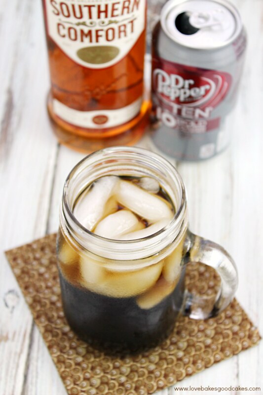 The Southern Doctor Cocktail in a glass jar with an open can of Dr. Pepper and a bottle of Southern Comfort.