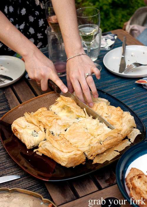 Phuoc cutting up her spanakopita cheese and spinach pie