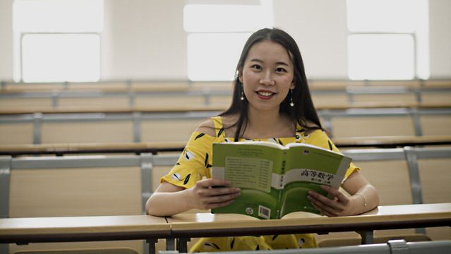 Photo of Li Nan (Beverly) holding a text book and looking at the camera.